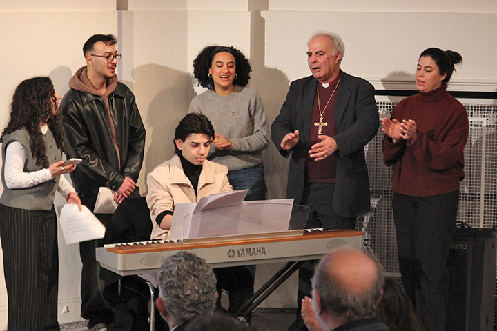 Der in den Ruhestand gegangene Bischof Sani Ibrahim Azar singt auf dem Jahresfest des Jerusalemsvereins auf der Bühne, zusammen mit vier jungen Erwachsenen und einem jungen Mann am Keyboard. Azar trägt ein großes goldenes Kreuz.