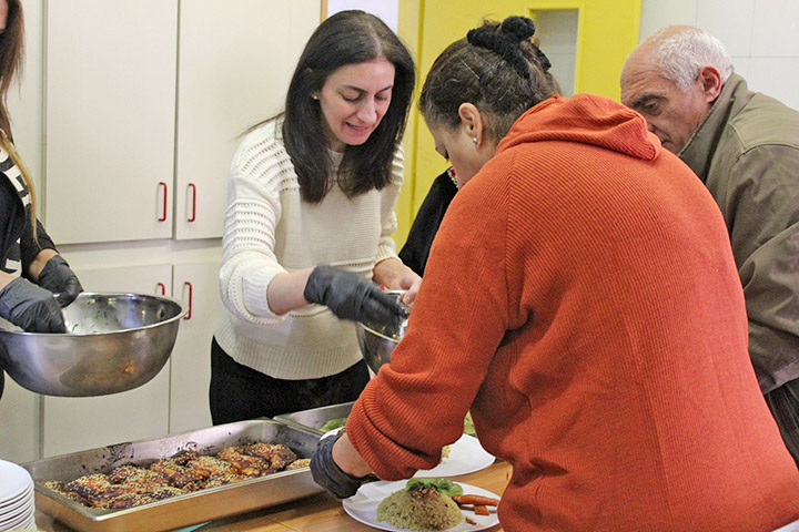 Rana Zeidan, die Leiterin der ELCJHL-Diakonie gibt in der Suppenküche in Beit Jala Essen an zwei ältere menschen aus.