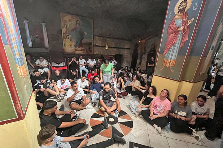 20-30 Jugendliche sitzen auf dem marmorboden eines Kirchenraums mit Fresken, Bildern und Skulpturen