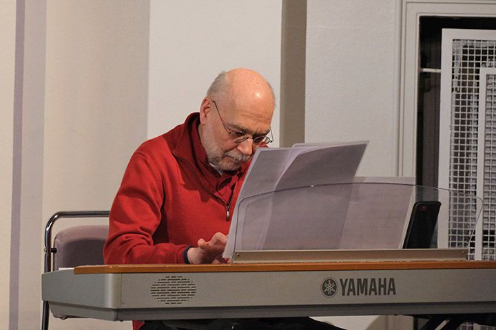 Der Pianist Albrecht Gündel-vom Hofe sitzt mit einem roten Pullover bekleidet am Keyboard.