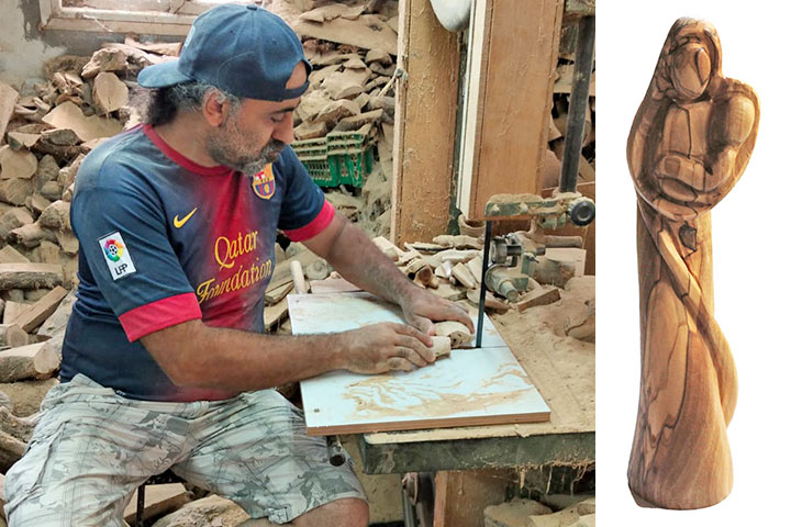 Ein Olivenholzschnitzer sitzt vor einer Säge und zerteilt einen Ast. Im Hintergrund ist Olivenholz aufgetürmt.